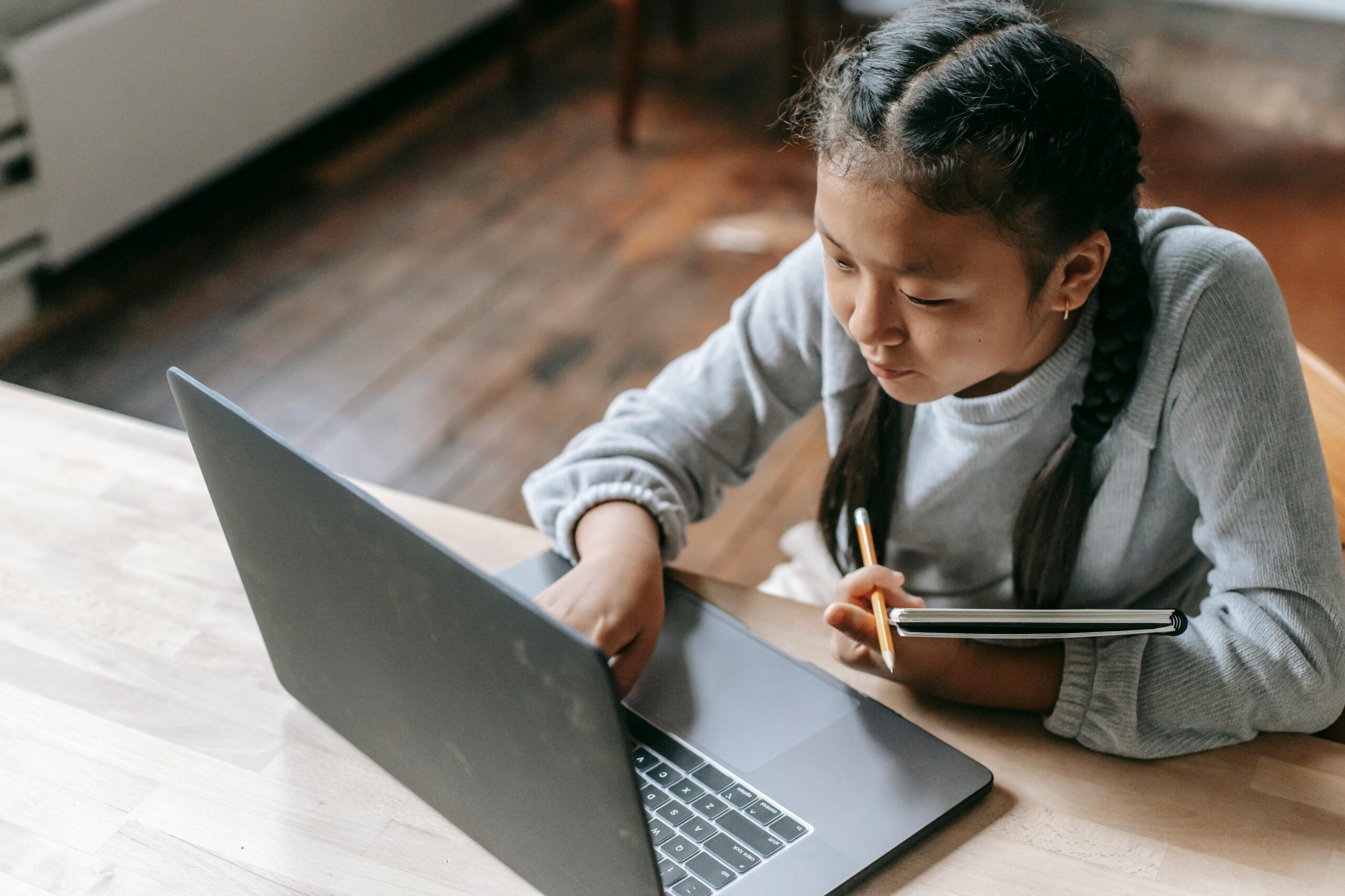 pexels-katerina-holmes-5905968 Mädchen mit schwarzen Haaren sitzt am Laptop und zeigt mit dem Finger auf den Bildschirm.